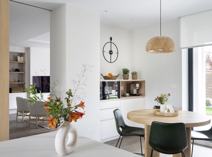 Comedor en cocina con mesa de madera, sillas contraste en negro y lámpara yute, panel corredero de madera acceso a salón, vivienda unifamiliar LAS, obra nueva y diseño de interiores y amueblamiento, Vitoria-Gasteiz