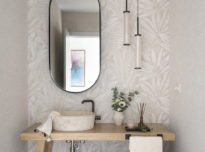 Aseo repisa en madera con lavabo pétreo y grifería en negro sobre encimera, papel pintado tonos neutro motivos florales y espejo ovalado perfilería en negro, vivienda unifamiliar LAS, obra nueva y diseño de interiores y amueblamiento, Vitoria-Gasteiz