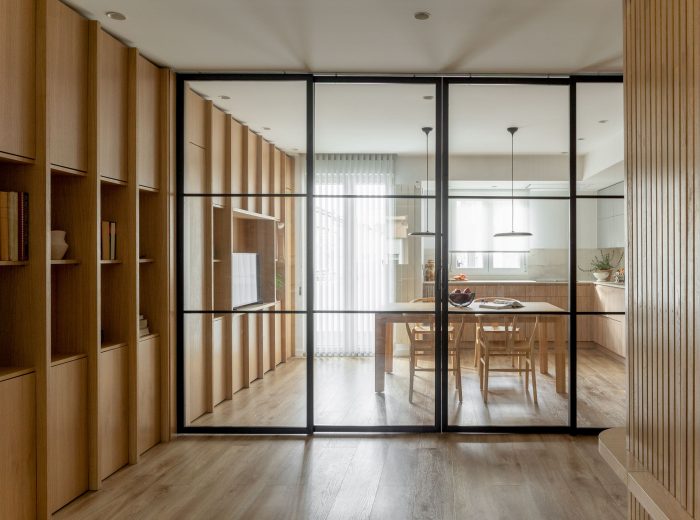 Vista de cocina desde salón con estantería de roble y cierre acristalado perfilería negra, reforma interior AG76, Vitoria-Gasteiz.