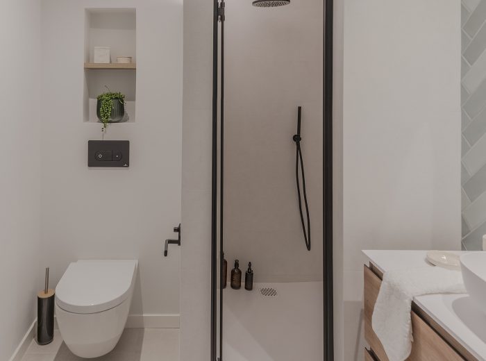 baño ensuite, inodoro suspendido con nicho decorativo superior, ducha con mampara de perfilería negra, reforma interior BG9, Vitoria-Gasteiz
