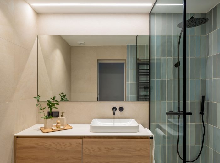baño con mueble en madera y lavabo semiempotrado con grifería empotrada en negro, azulejos rectangulares en posición vertical color azul en pared ducha, reforma interior y diseño de interiores y amueblamiento EF13, Vitoria-Gasteiz