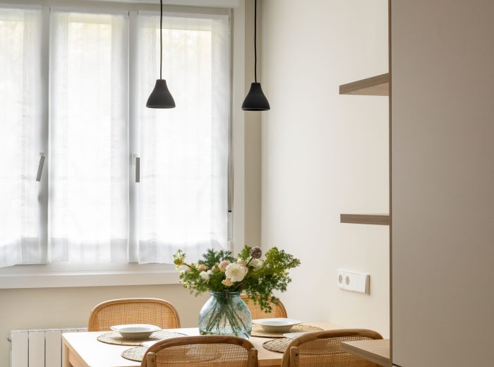 Comedor  con mesa de madera y sillas de ratán y lámparas suspendidas en negro, reforma interior y diseño de interiores y amueblamiento EF13, Vitoria-Gasteiz