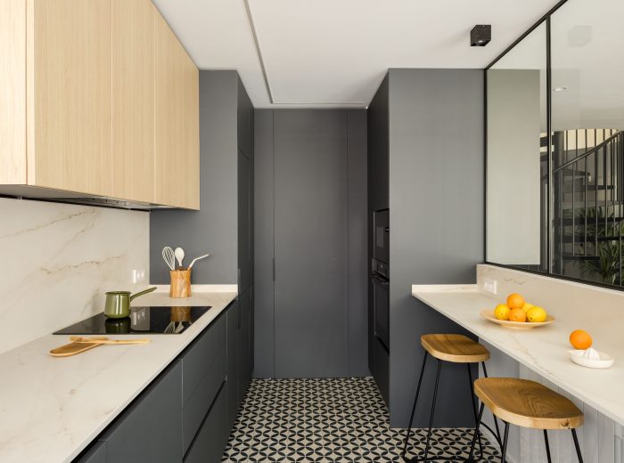 Cocina optimizada en diseño y funcionalidad, incorporando un walk-in closet que sirve de lavandería en proyecto FL9, Vitoria-Gasteiz.