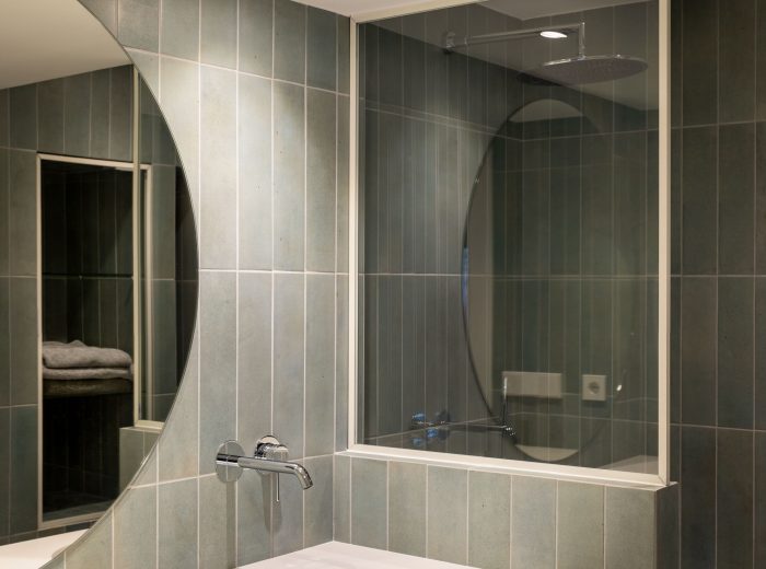 baño en suite revestido con azulejo Niza Green y mampara a medida apoyada sobre murete separador, reforma integral O50 en Vitoria-Gasteiz.