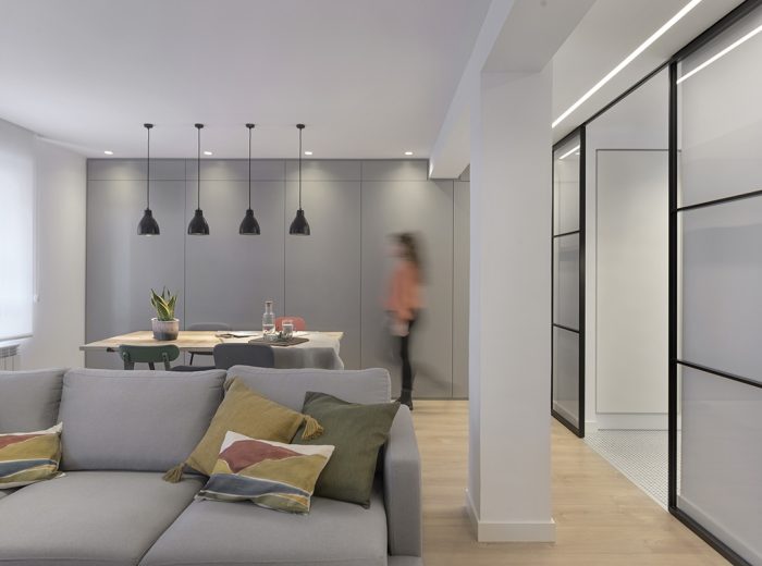 conexión visual entre salón, comedor y cocina mediante lámparas negras y cristalera con perfilería metálica, reforma RB5 en Vitoria-Gasteiz.