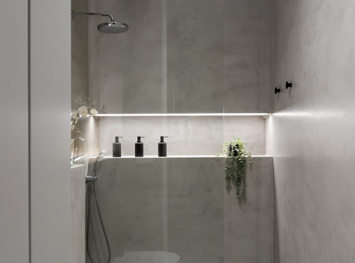 Detalle de baño en suite con ducha continua a ras de suelo, nicho integrado y mampara de vidrio fijo, reforma integral VG6 en Vitoria-Gasteiz.