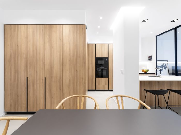 Comedor conectado con cocina a medida mediante paneles de madera y encimera porcelánica Inalco, reforma integral VG6 en Vitoria-Gasteiz.