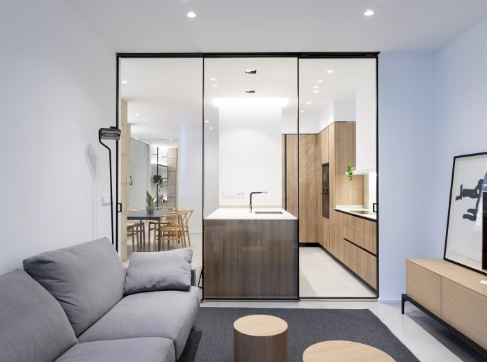 salón conectado visualmente con la cocina mediante cristalera de perfilería de aluminio negro, reforma integral VG6 en Vitoria-Gasteiz.