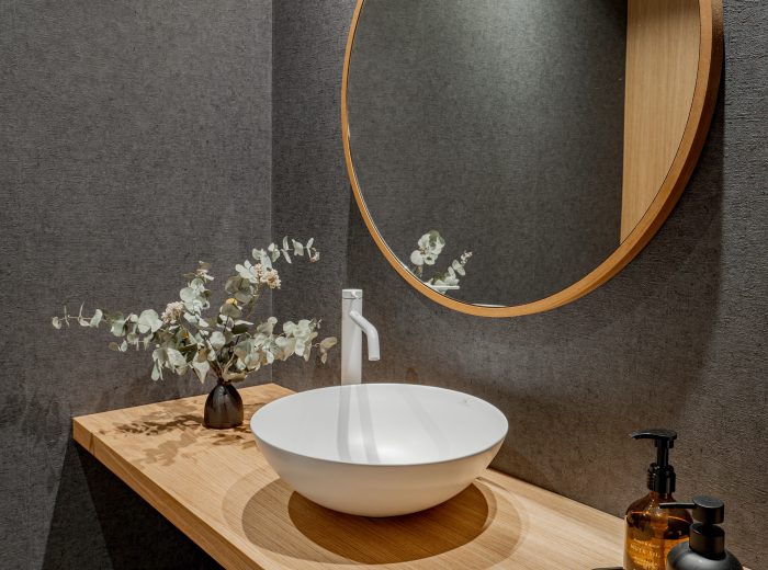 Aseo de oficina con pared revestida en papel pintado vinílico y lavabo sobre encimera de madera de roble, diseño de interiores elegante y funcional en proyecto VG66, Vitoria-Gasteiz