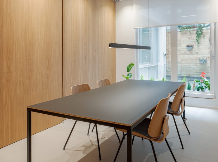 Vista completa de oficina con mesa central, paneles correderos abiertos, diseño de interiores multifuncional y adaptable en proyecto VG66, Vitoria-Gasteiz