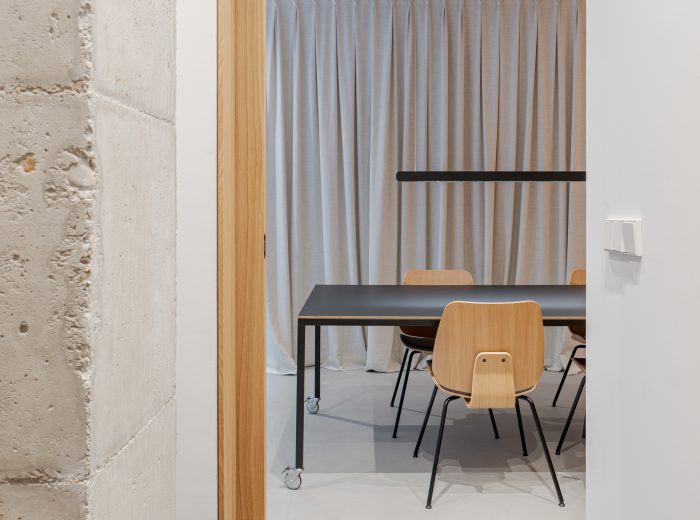 Vista desde el acceso a la vivienda contigua con mesa central de reunión y cortina que oculta gimnasio, diseño de interiores funcional y ordenado en proyecto VG66, Vitoria-Gasteiz
