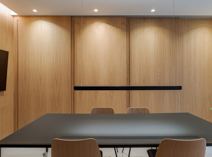 Sala de reuniones con paneles correderos de madera de roble cerrados, garantizando privacidad y funcionalidad en diseño de interiores multifuncional en proyecto VG66, Vitoria-Gasteiz