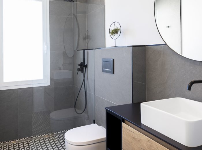 baño con suelo hidráulico y revestimiento de gran formato, con grifería y detalles en negro que unifican el lenguaje del proyecto, reforma integral ZB4 en Vitoria-Gasteiz.