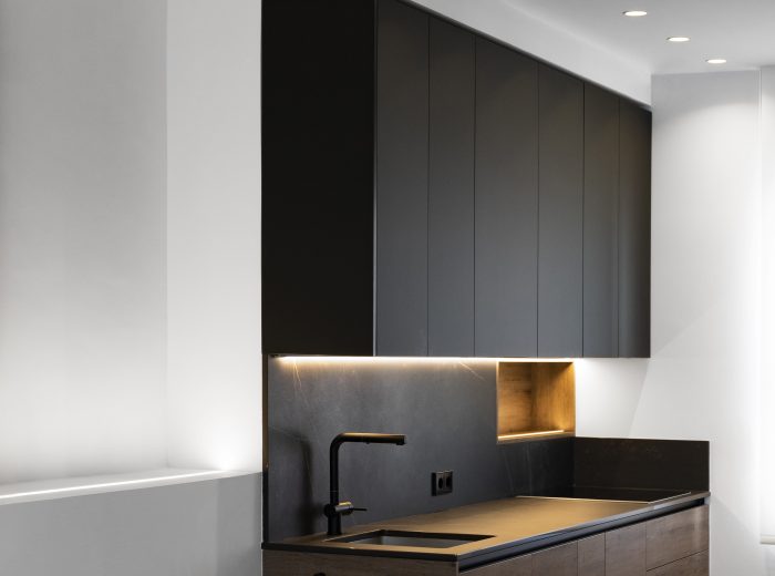 Cocina a medida con frentes en madera, encimera porcelánica oscura y módulos superiores lacados en negro con almacenaje integrado, reforma integral ZB4 en Vitoria-Gasteiz.