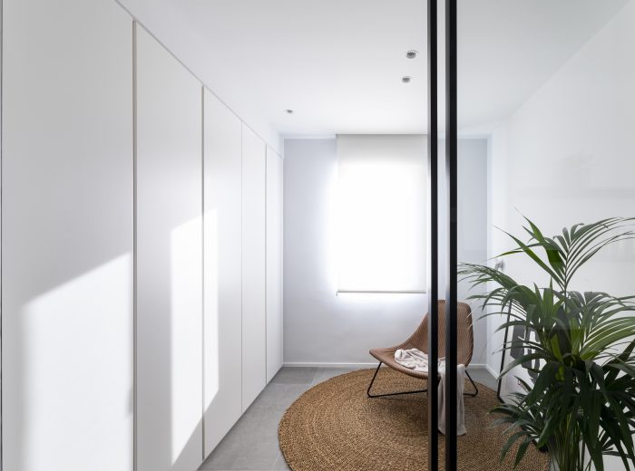 habitación de invitados conectada visualmente mediante cristalera de perfilería negra y armario empotrado lacado en blanco con uñero fresado, reforma integral ZB4 en Vitoria-Gasteiz.